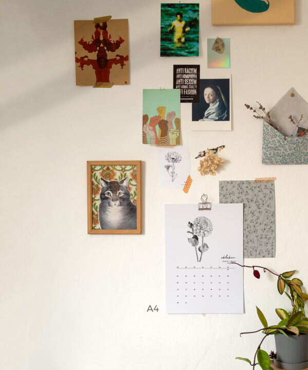 Kalenderblatt mit handgezeichneten Blumen zwischen anderen Bildern an der Wand